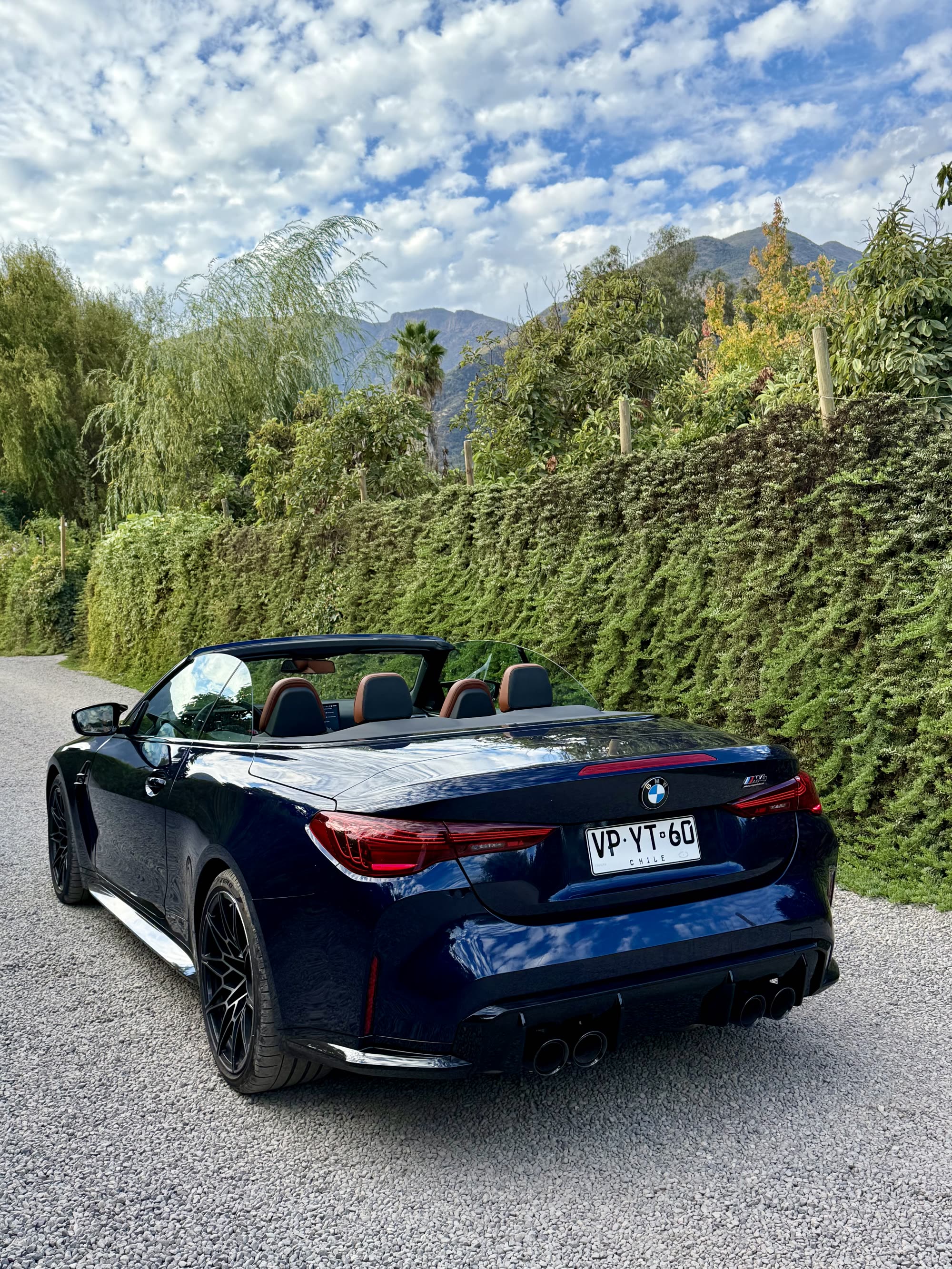 Vista trasera del BMW M4 Cabriolet en camino de campo con montañas
